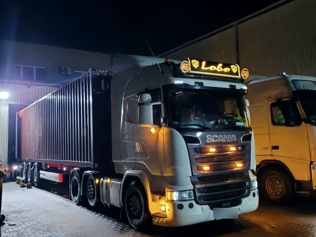 Ciągnik LOBOTRANSPORT nocą przy bazie, z zapalonymi światłami
